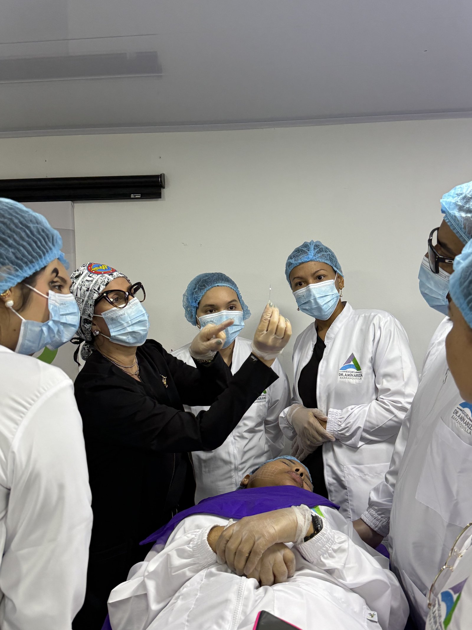 Médica aplicando procedimiento facial inyectable bajo supervisión durante el diplomado